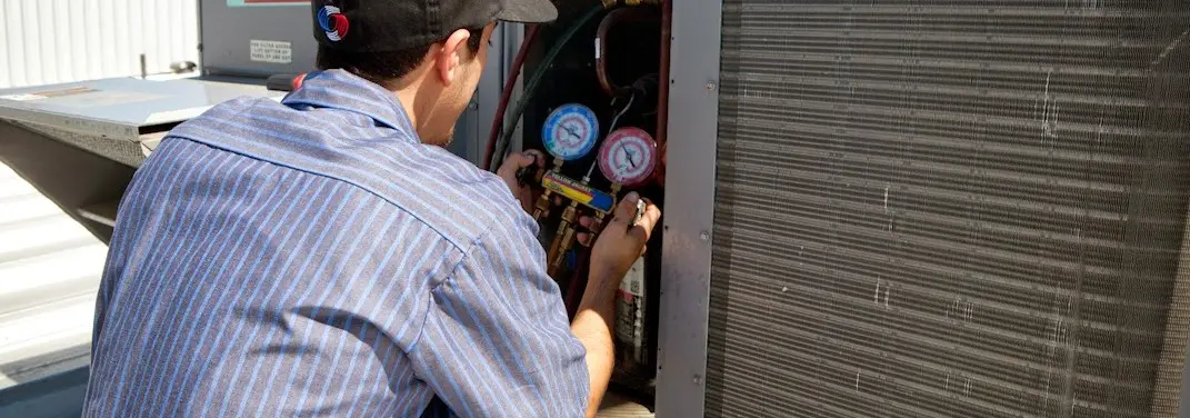 HVAC technician servicing a condenser unit in Mantua